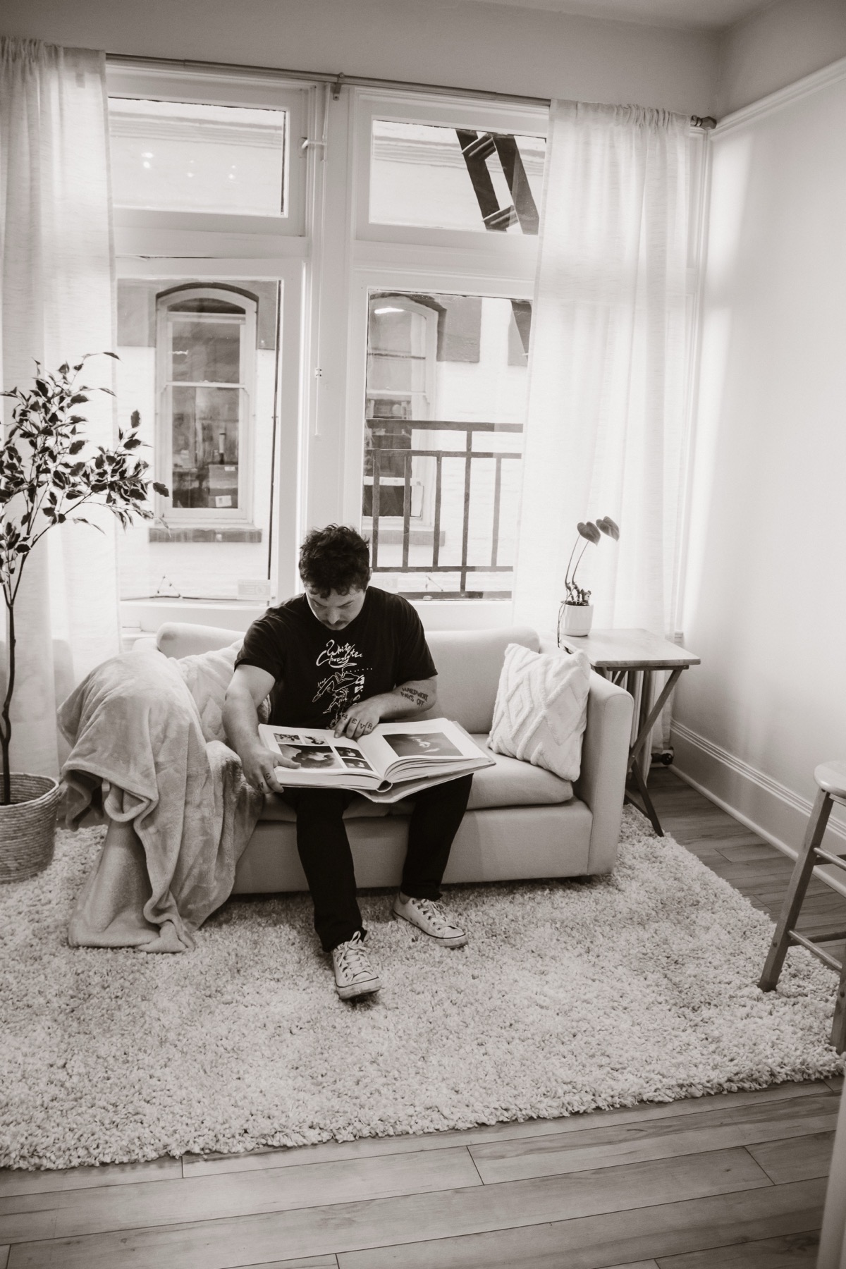 Black and white portrait on the Studio Rose couch with an open book.